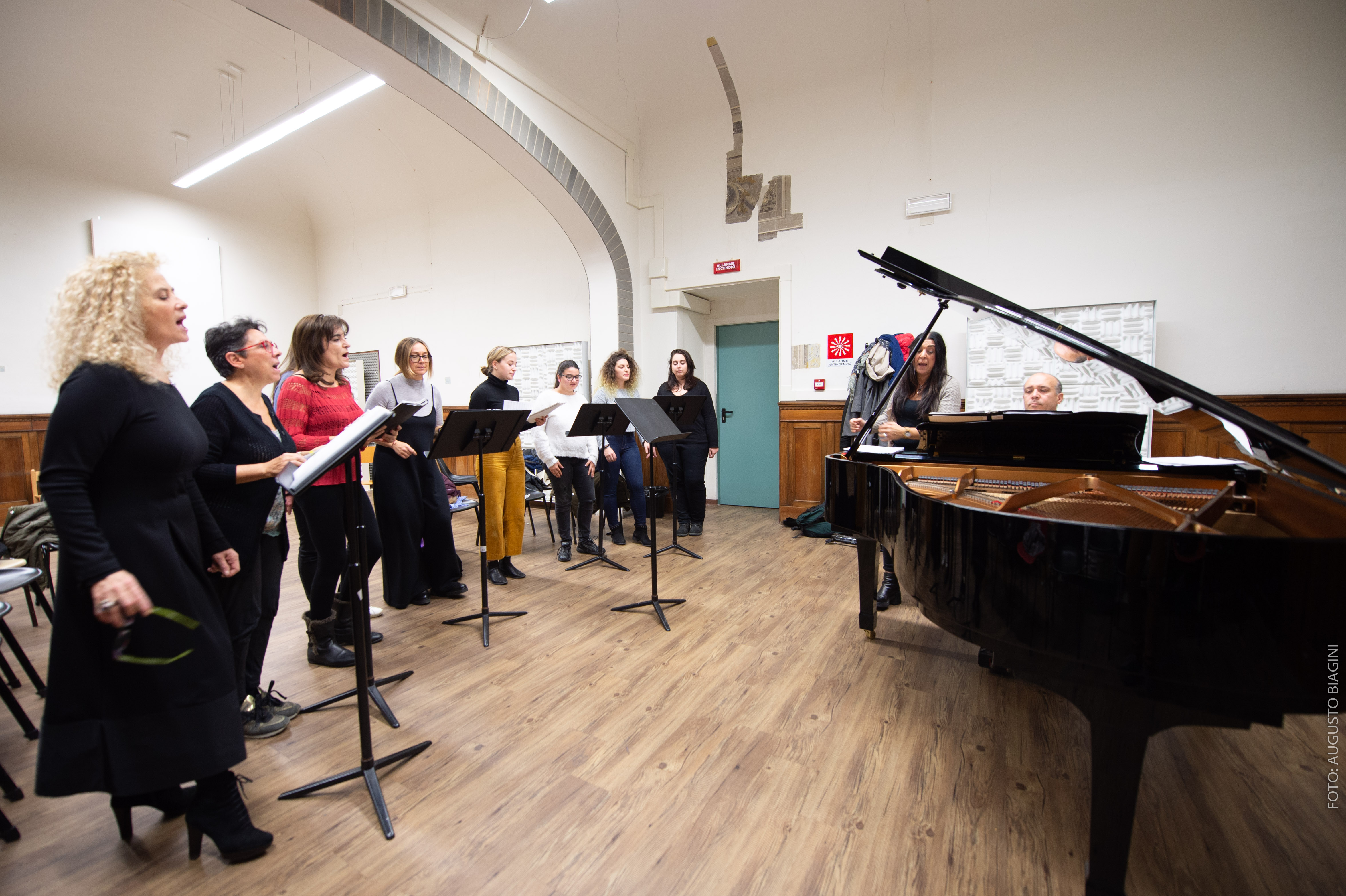 Gruppo di persone che canta attorno al pianoforte